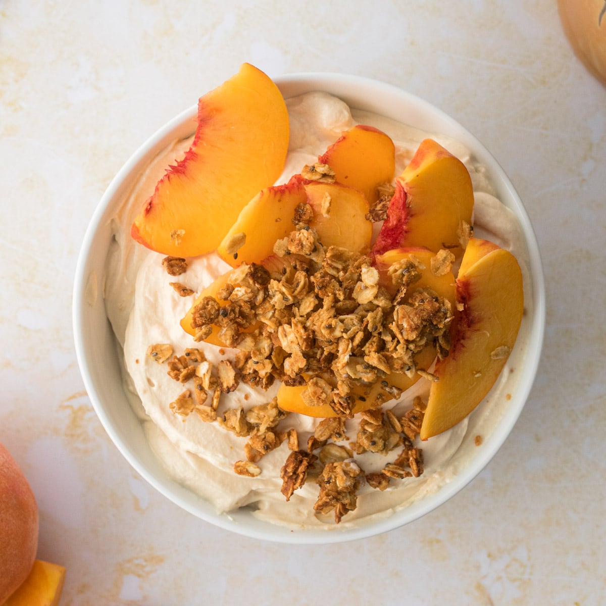 close up of yogurt with granola and yellow peach slices