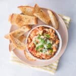square image of tomato and white beans in dish with bread