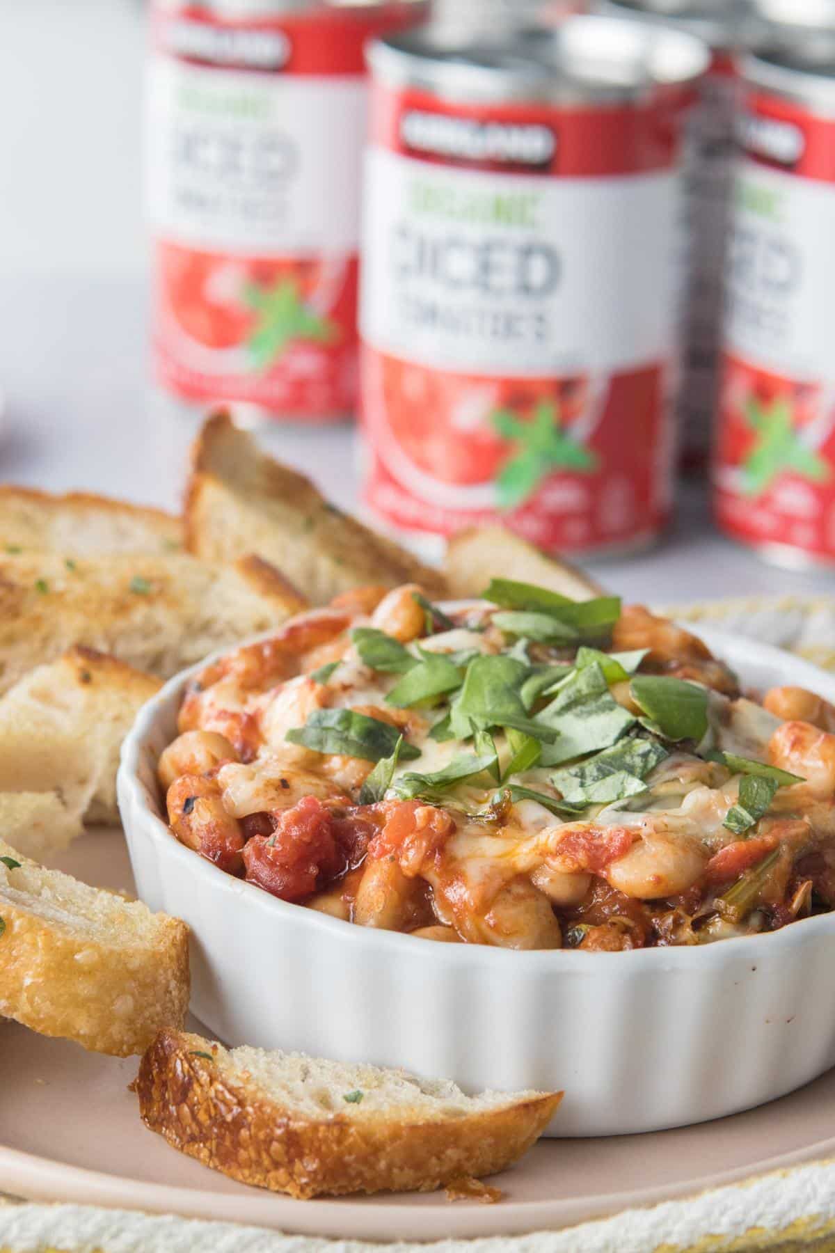 white bowl with white beans, tomatoes basil in it