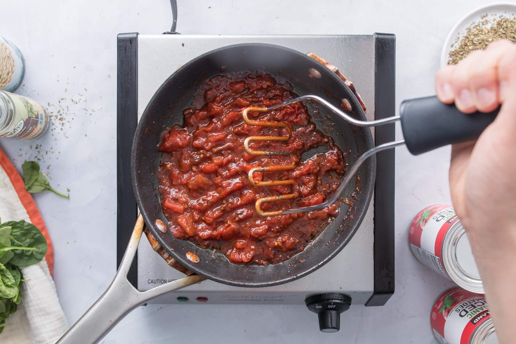 mashing tomatoes in skillet