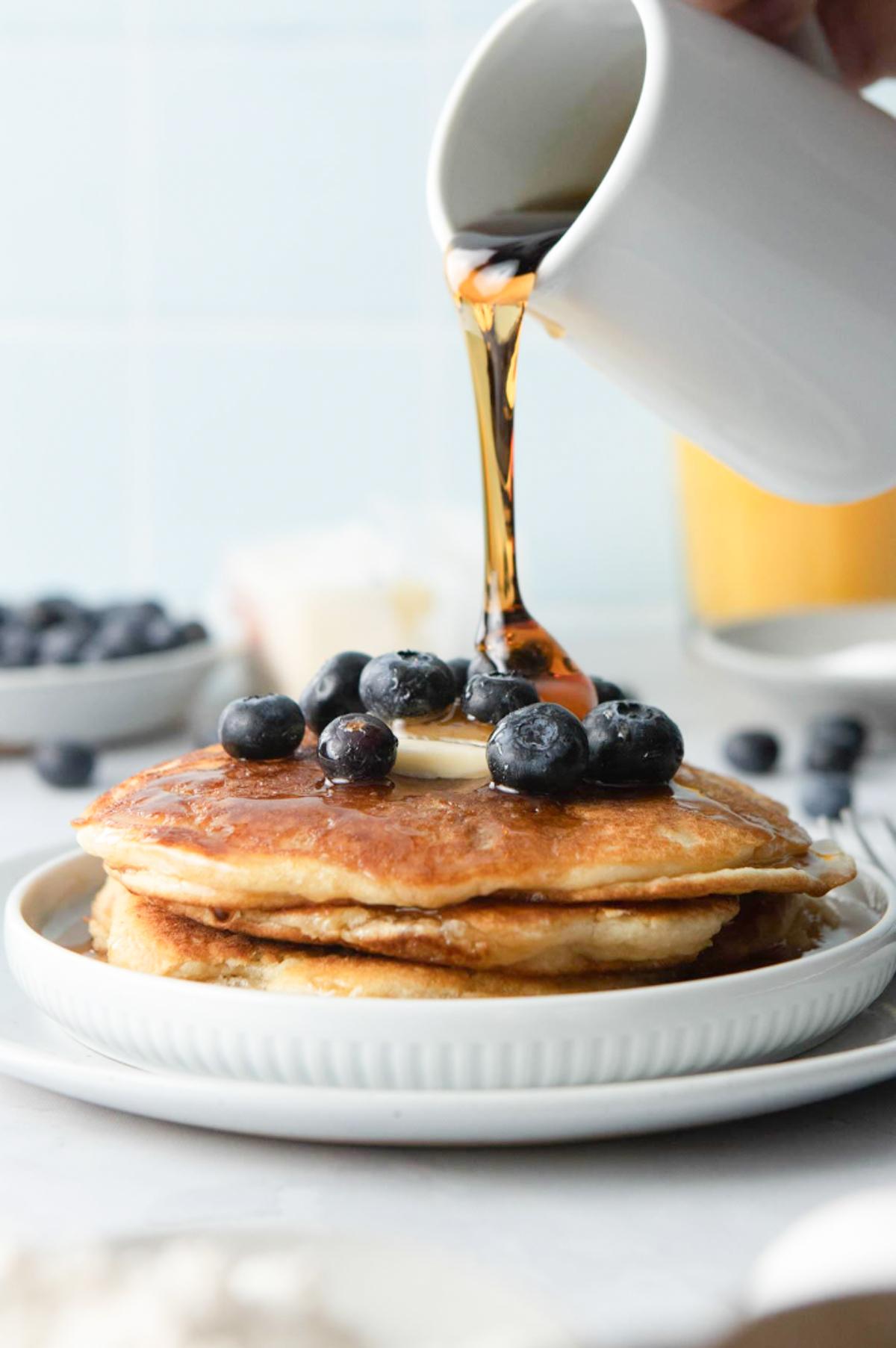 pouring syrup over pancakes