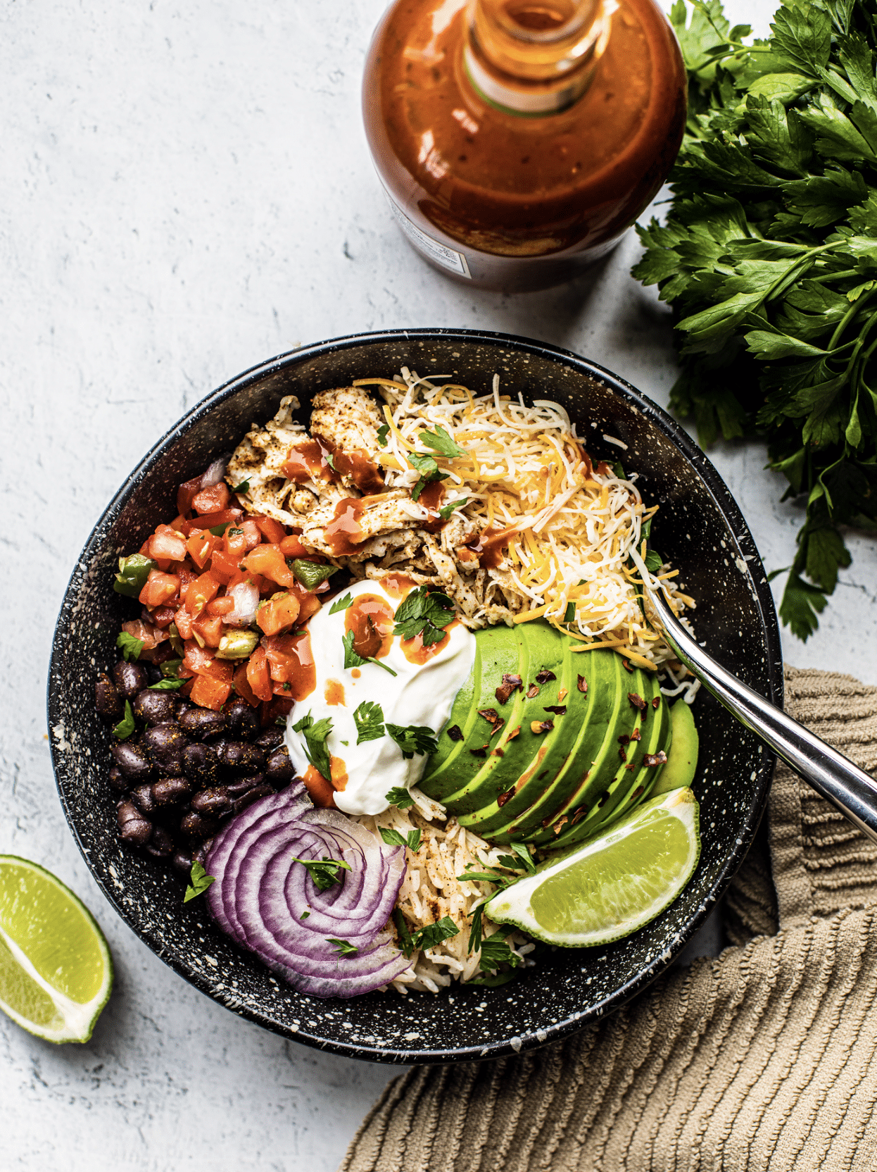 burrito bowl with cheese, avocado, lime, onions, beans, tomatoes