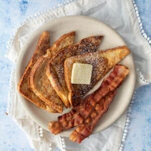 slices of french toast, bacon, butter on plate