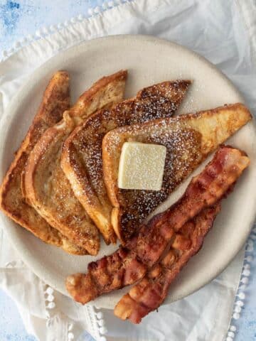 slices of french toast, bacon, butter on plate