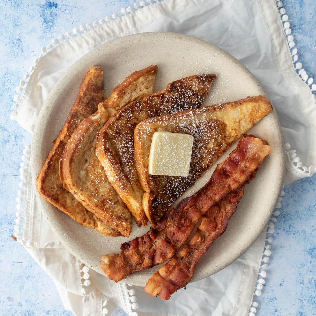 slices of french toast, bacon, butter on plate