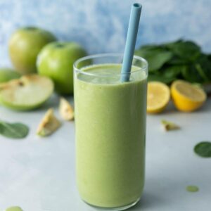 glass full of green drink with blue straw in it