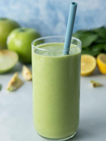 glass full of green drink with blue straw in it