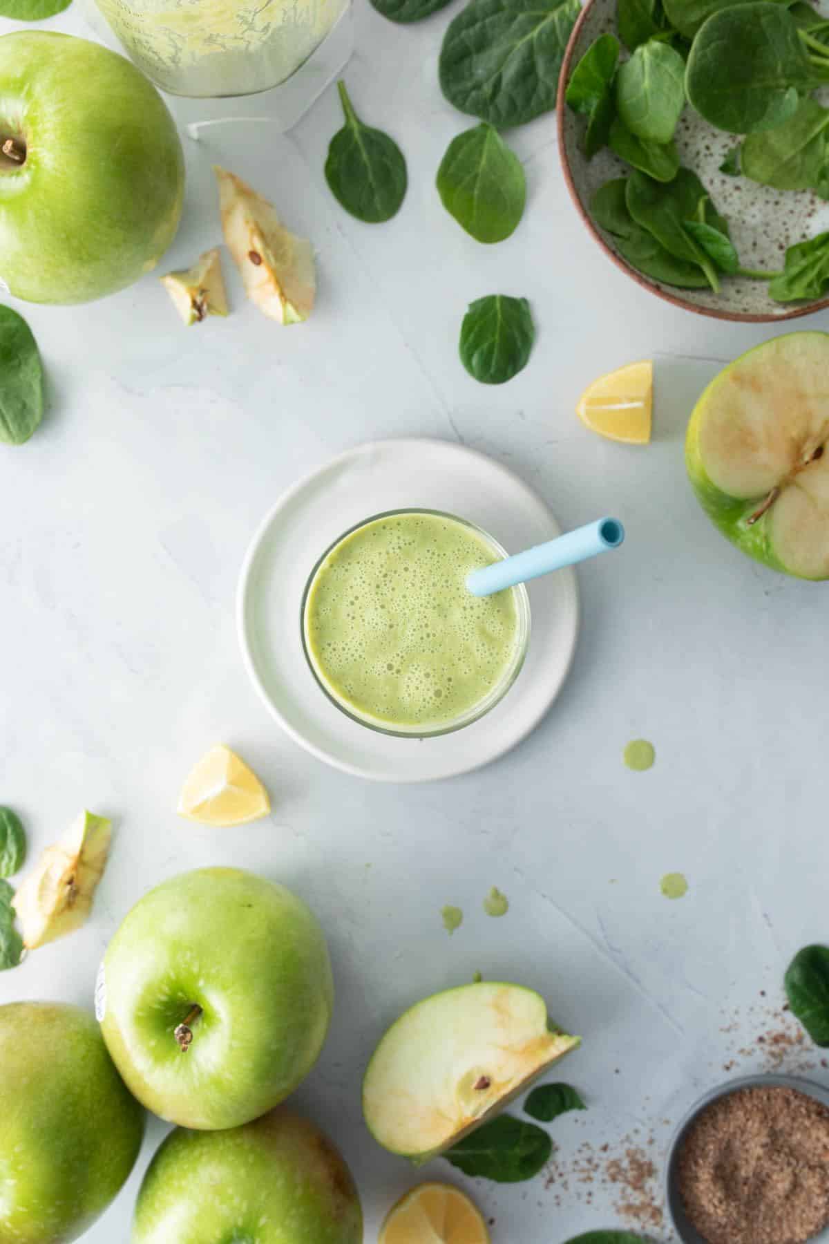 green drink in glass with ingredients surrounding it