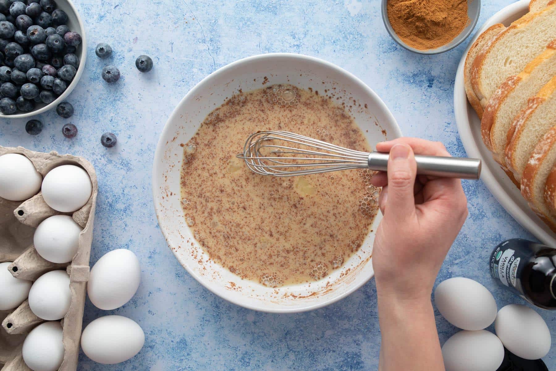 hand whisking cinnamon and egg mixture in bowl