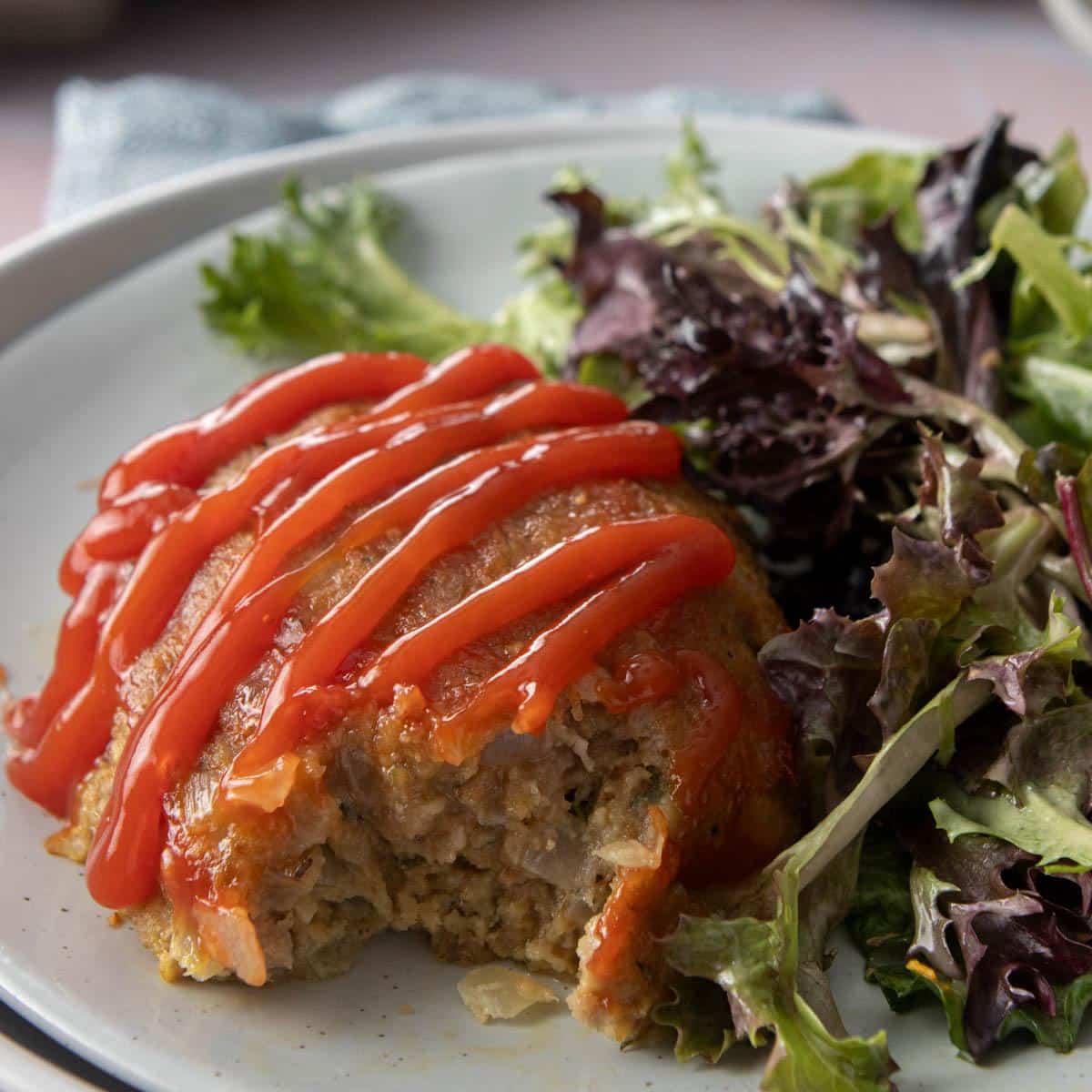 bite out of meatloaf with ketchup and salad