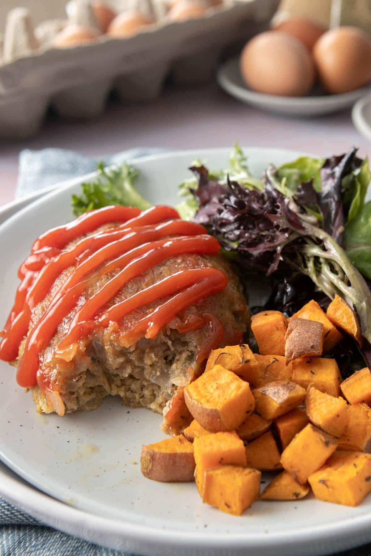 bite out of meatloaf next to sweet potatoes and salad