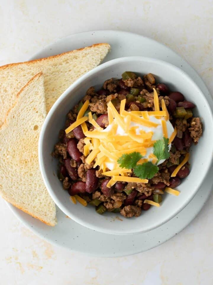 chili with toppings and slices of bread on side