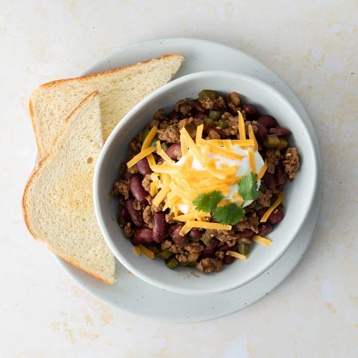 chili with toppings and slices of bread on side