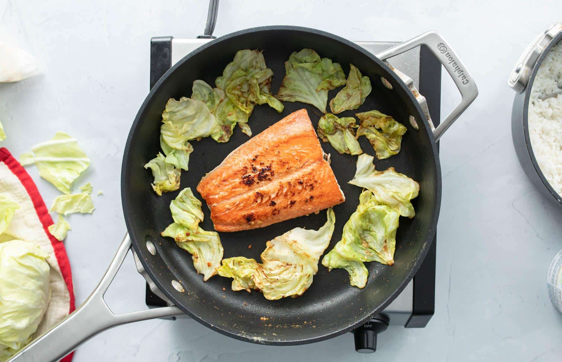 salmon and wilted cabbage cooking in pan