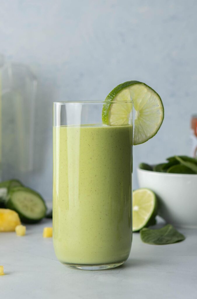 green smoothie in glass with lime slice on glass