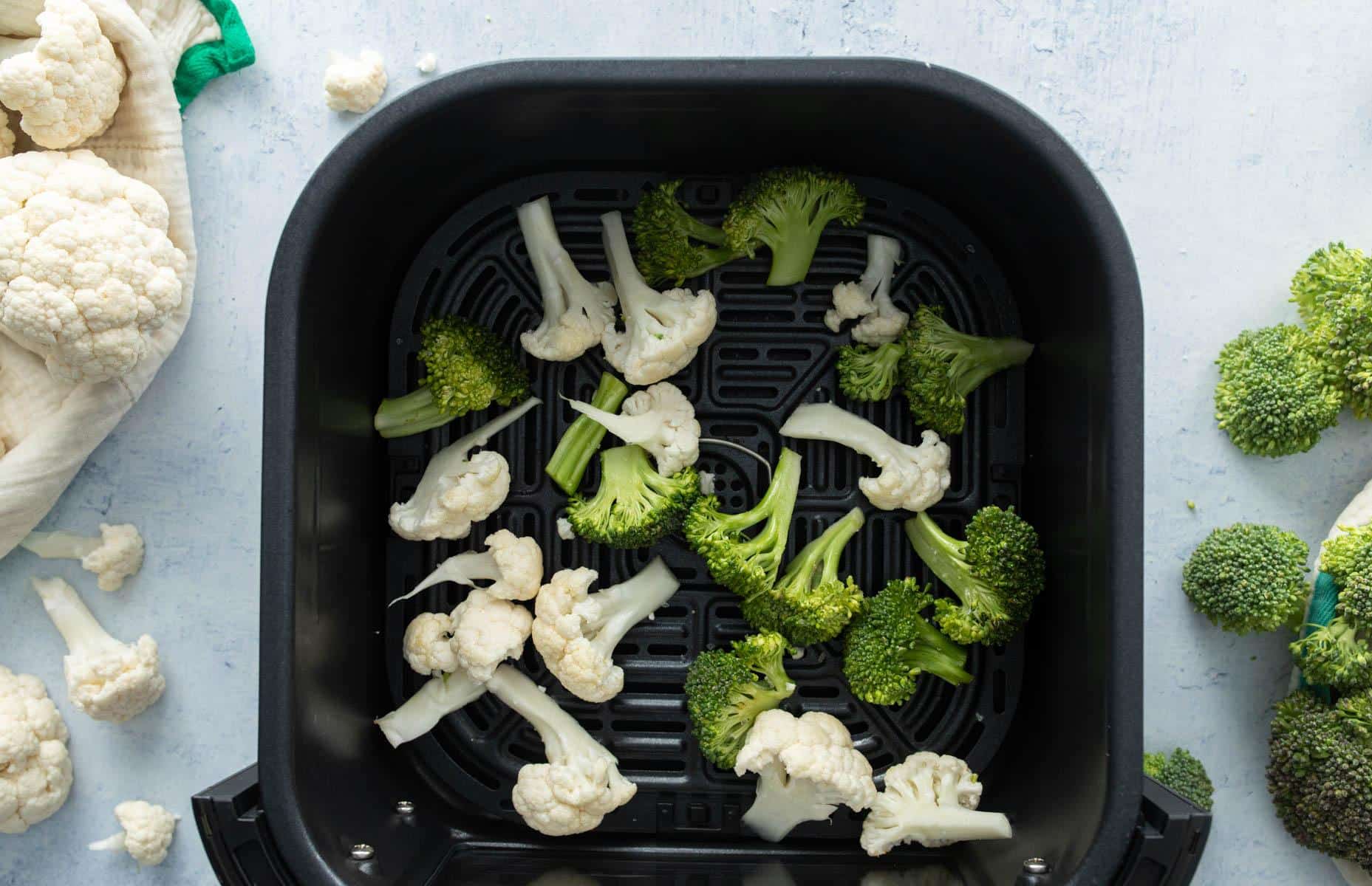 raw broccoli and cauliflower in air fryer basket