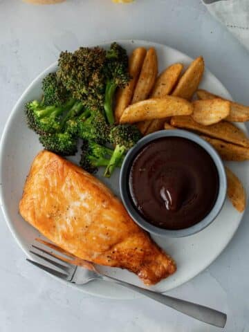 plate full of salmon, roasted broccoli, fries, bbq sauce