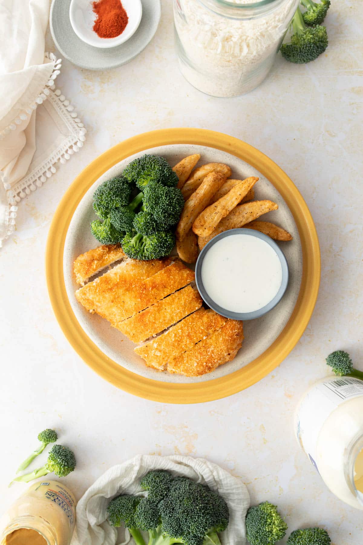 sliced panko crusted chicken, broccoli, fries, ranch on yellow plate