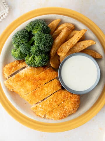 sliced panko crusted chicken, side dishes, ranch on yellow plate