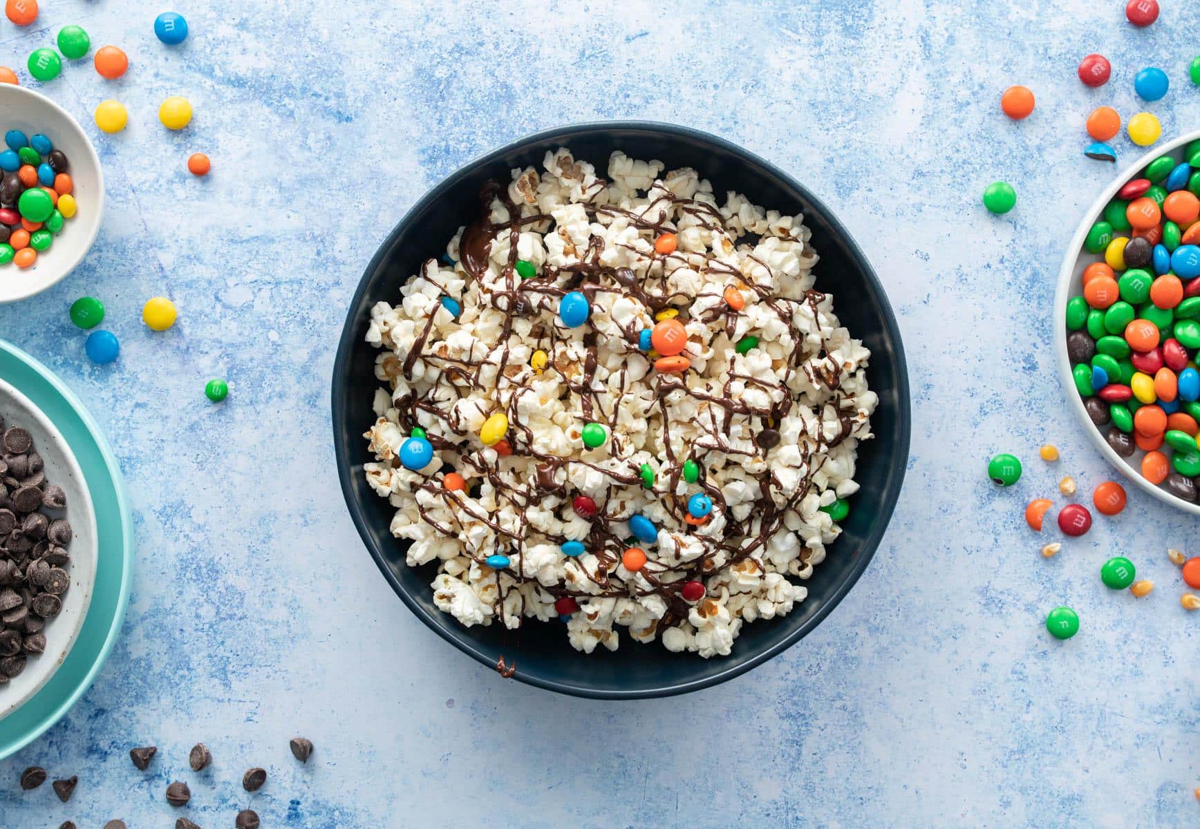 bowl filled with popcorn, candies, and chocolate drizzle