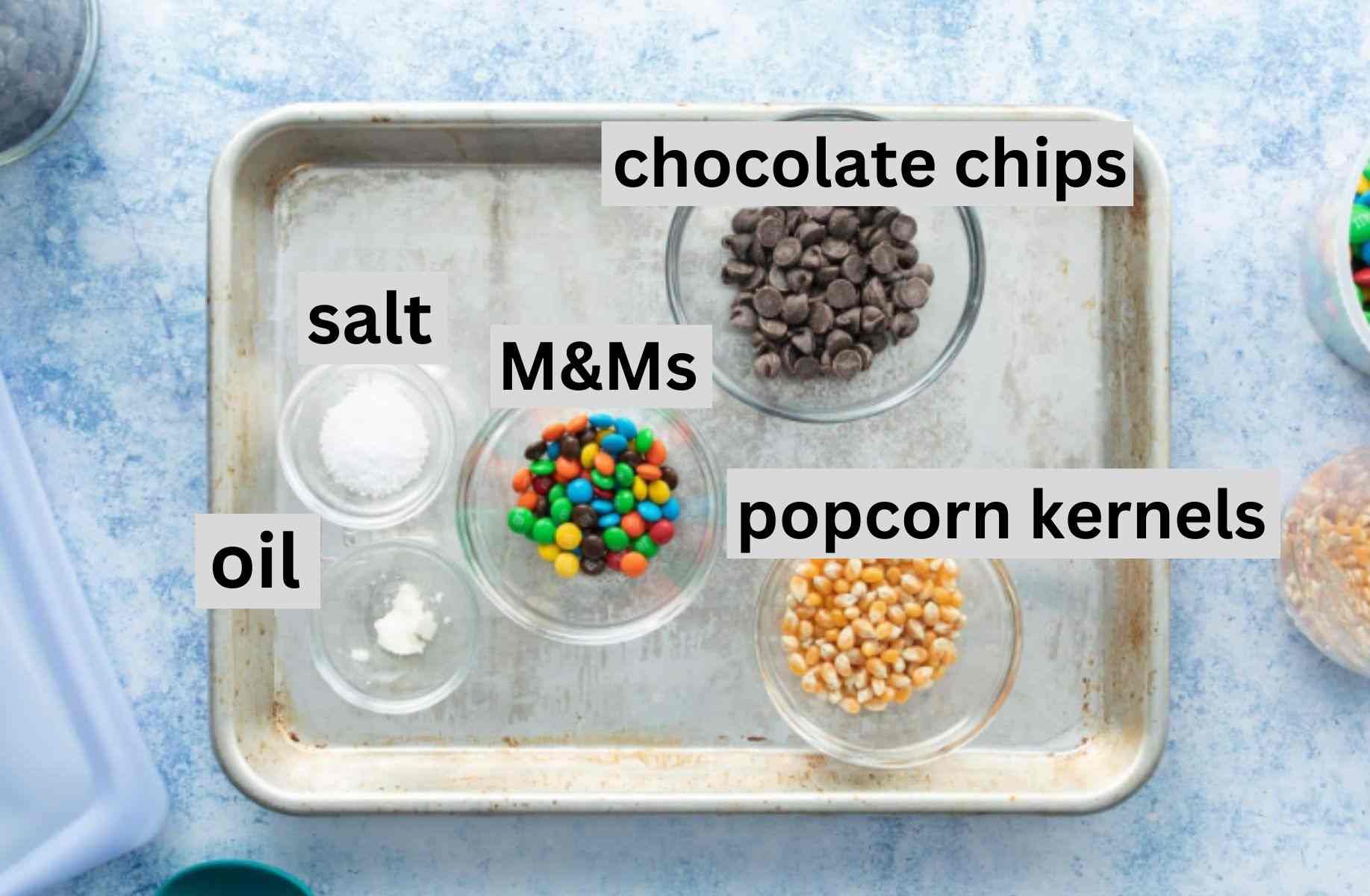 chocolate chips, popcorn kernels, m&ms, salt on baking tray