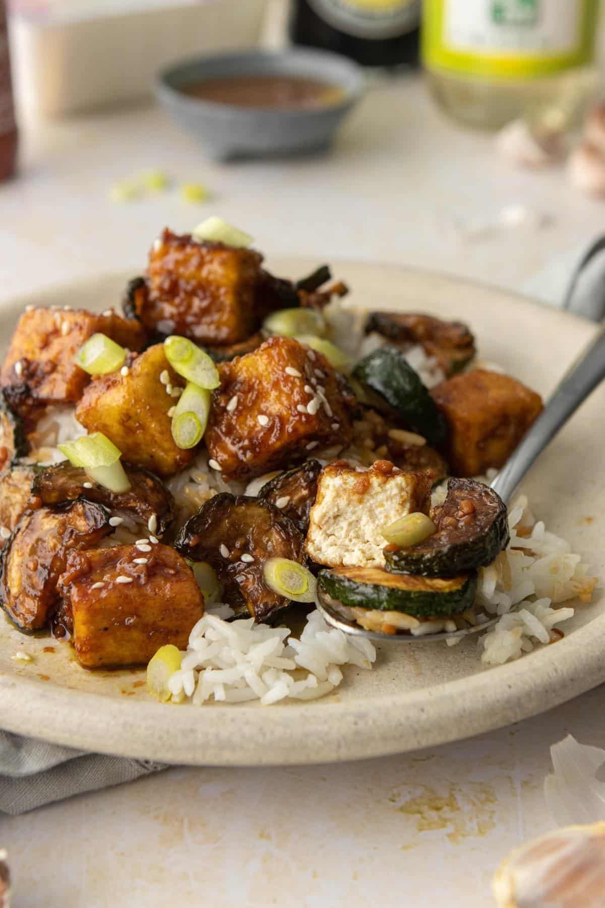 cut piece of honey garlic tofu on a spoon, on plate