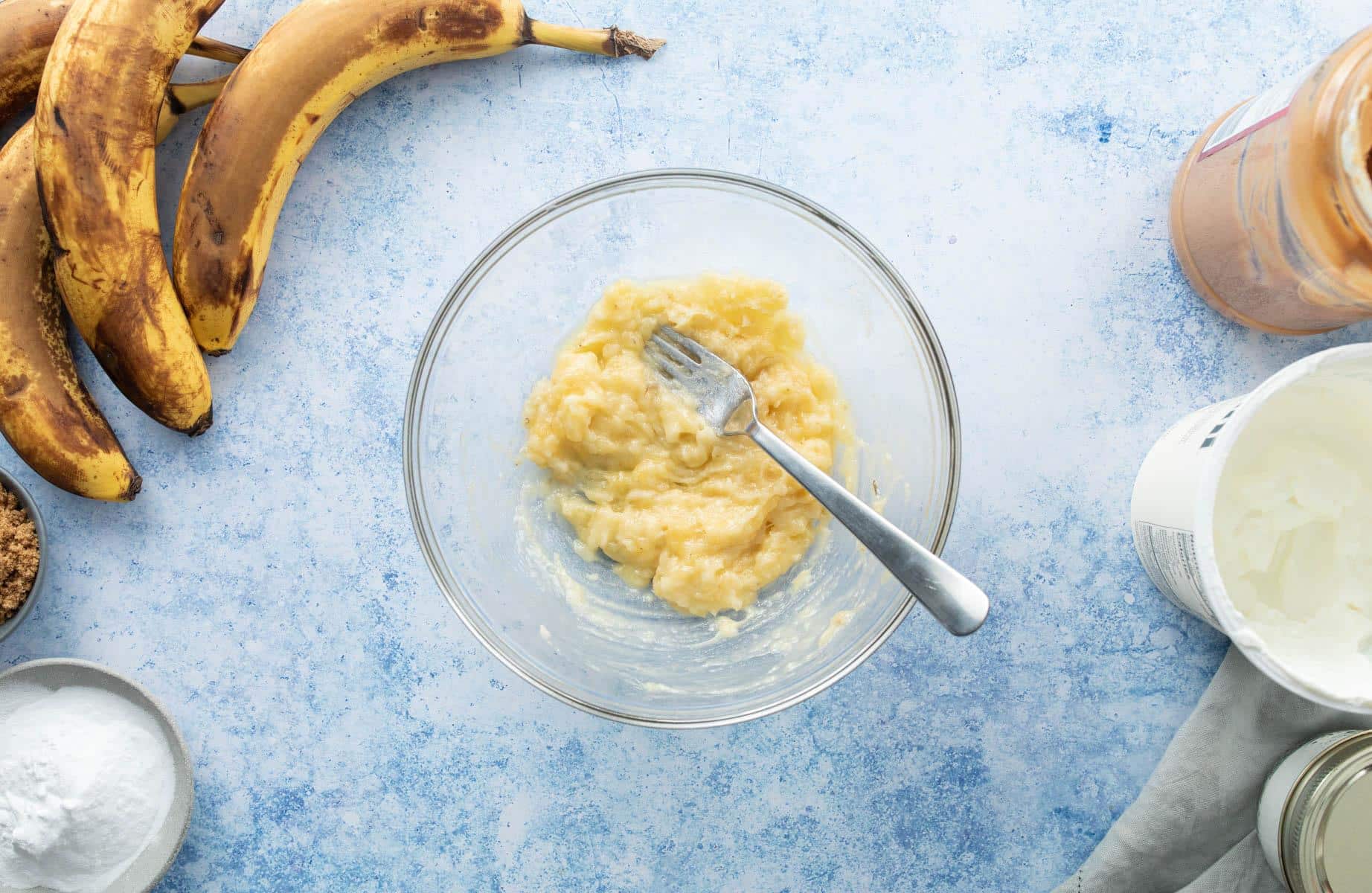 fork in mashed bananas in glass bowl