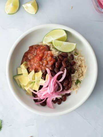 rice and beans, onions, salsa, avocado, lime wedges in bowl