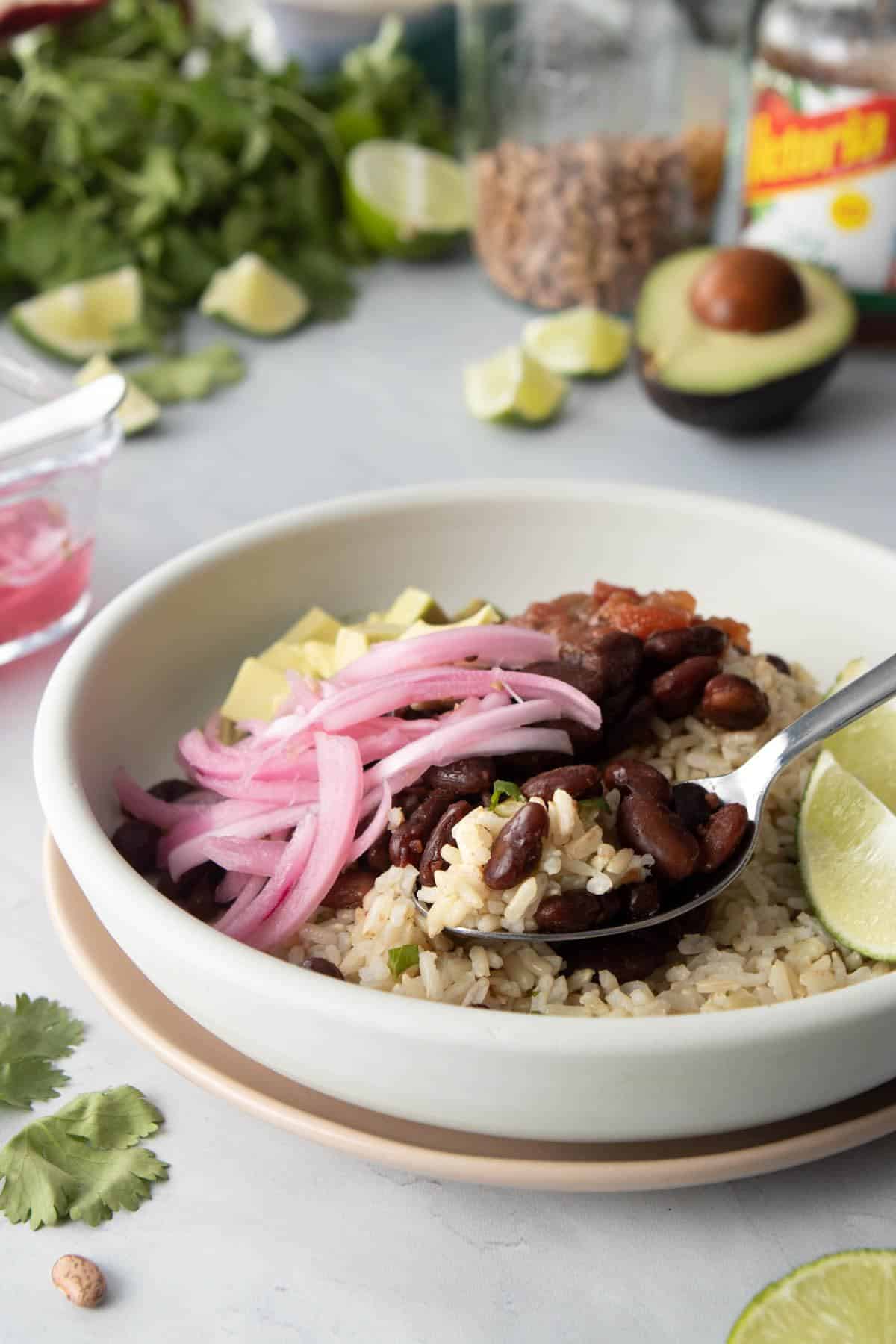 spoonful of pinto beans and rice in bowl with toppings