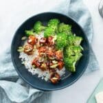 broccoli, saucy tofu over rice in blue bowl