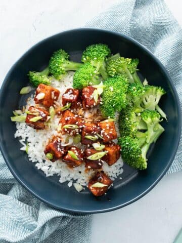 broccoli, saucy tofu over rice in blue bowl