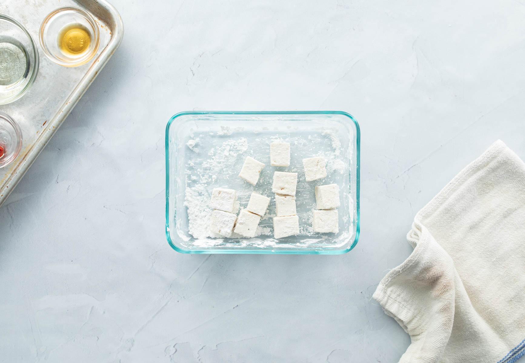 cubes of tofu with cornstarch in container