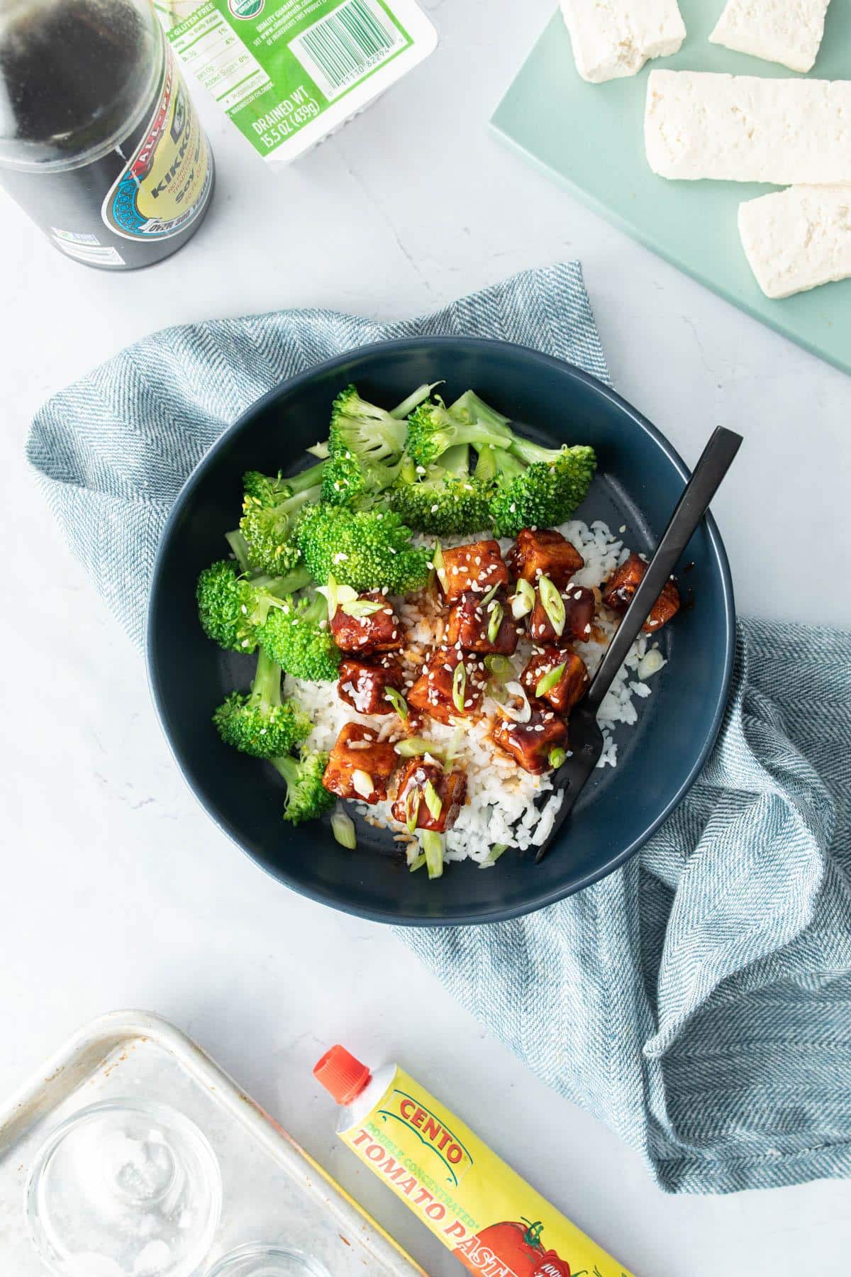 tofu with sauce over rice, broccoli in blue bowl