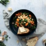 blue bowl full of white beans, vegetables and bread with butter