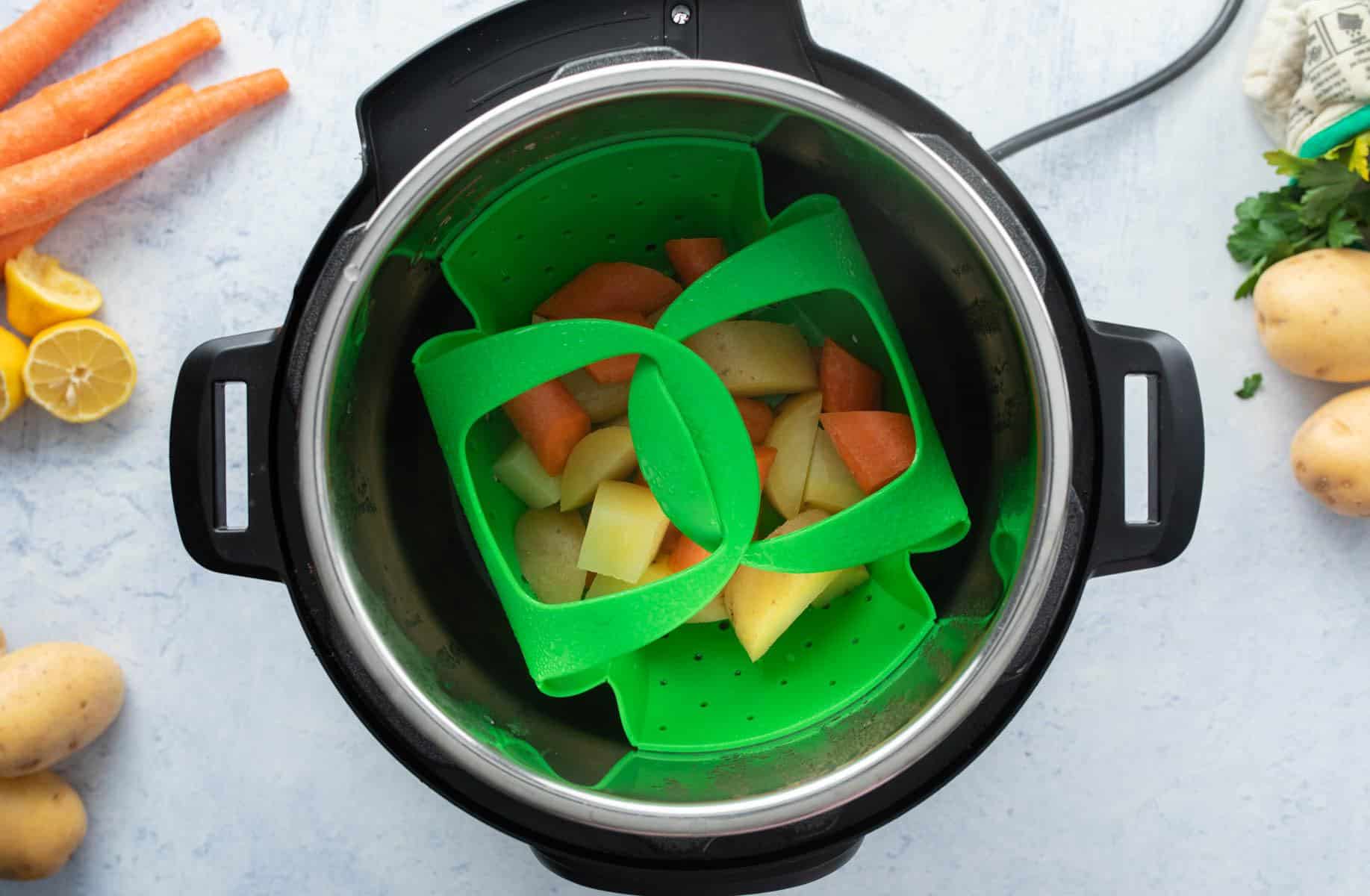 potatoes, carrots in green steamer basket in Instant Pot