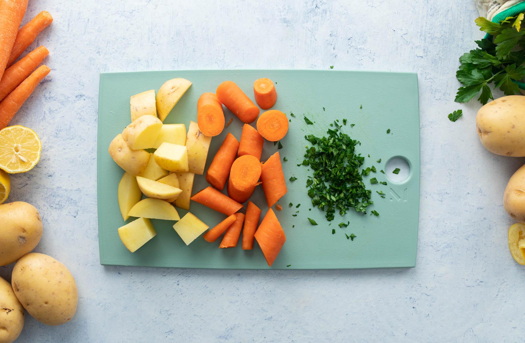 Cut potatoes, carrots, parsley on green cutting board