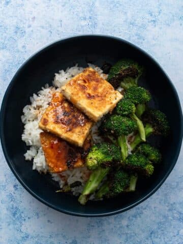 three slices of fried tofu, broccoli in bowl