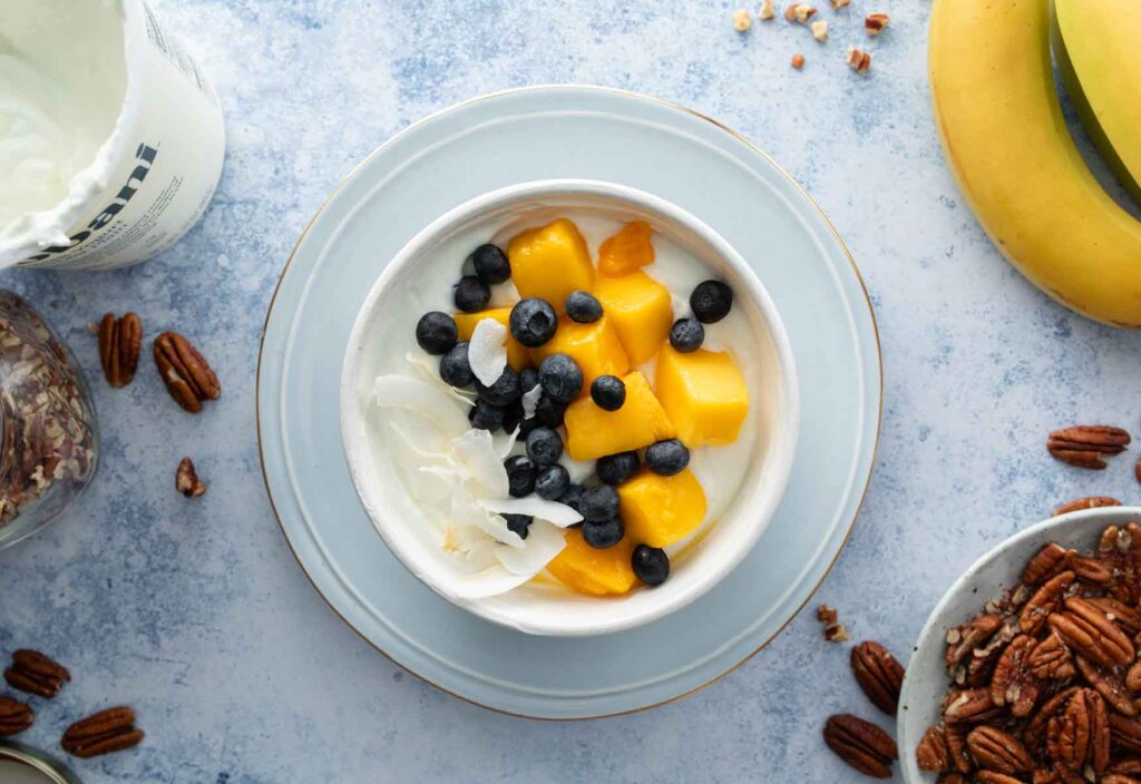 coconut pieces, mango chunks, and blueberries on yogurt