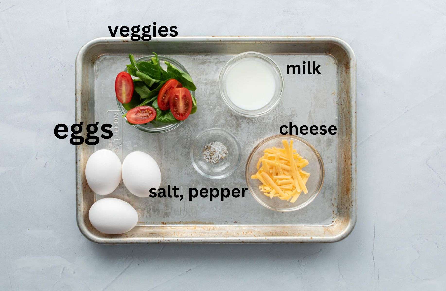 eggs, cheese, vegetables on baking sheet with labels