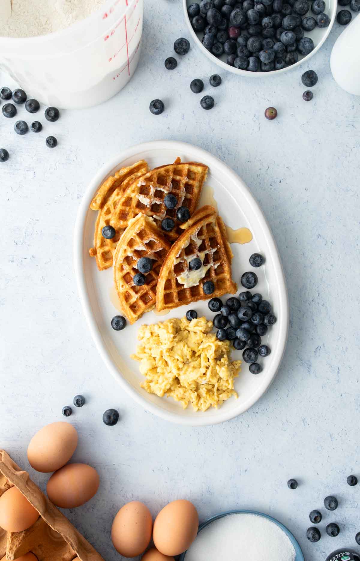 quartered waffle, scrambled eggs, and blueberries on oval plate