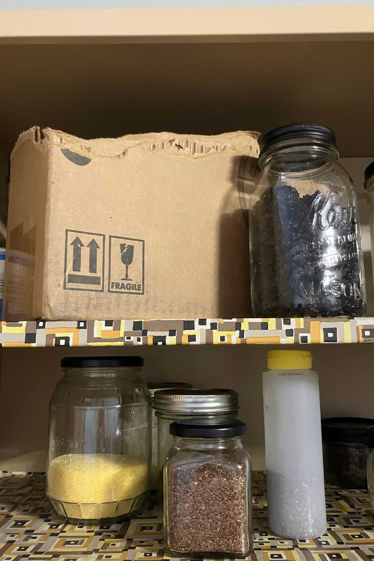 cardboard box and jars of pantry ingredients on two shelves