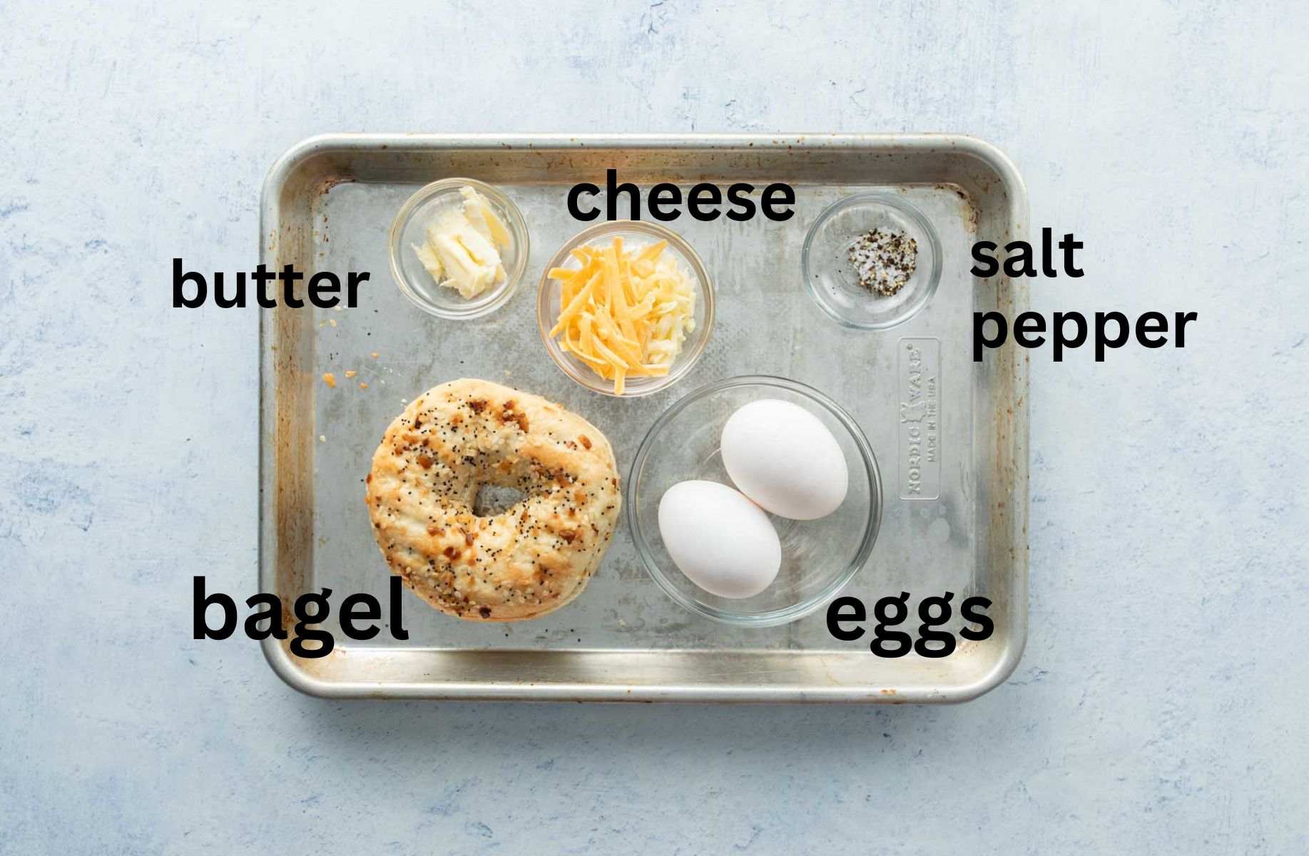 bagel with eggs ingredients on baking sheet, with labels