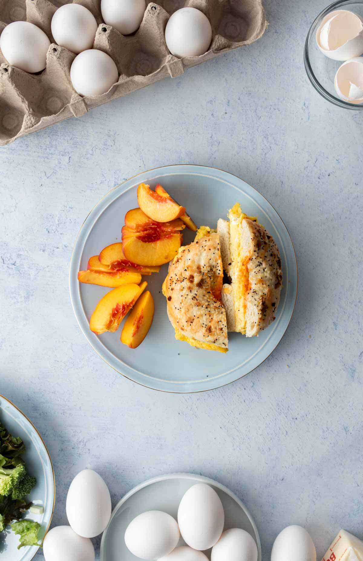 two slices of bagel with eggs and peaches on plate