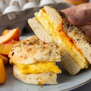 two slices of egg bagel sandwich held by hand