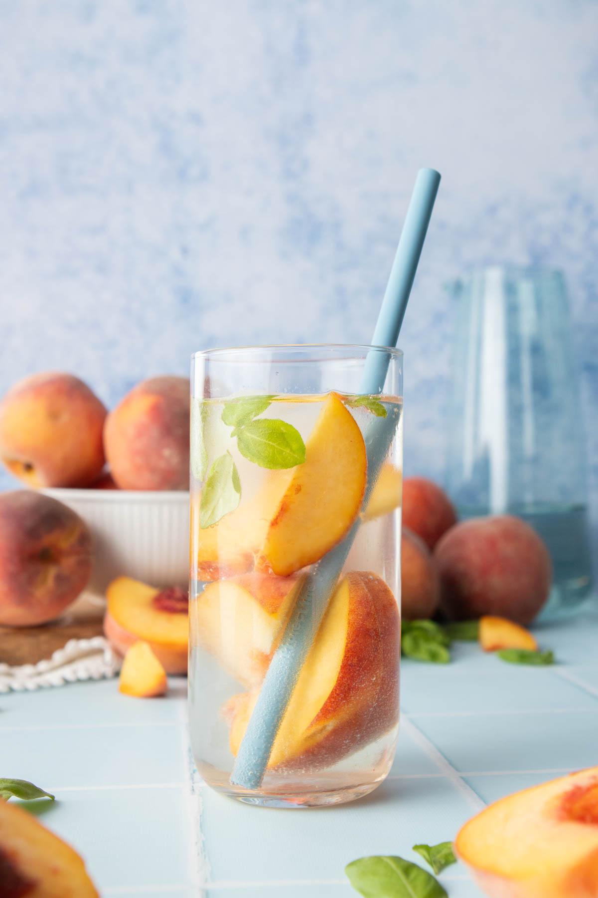 glass of peach water with straw in it