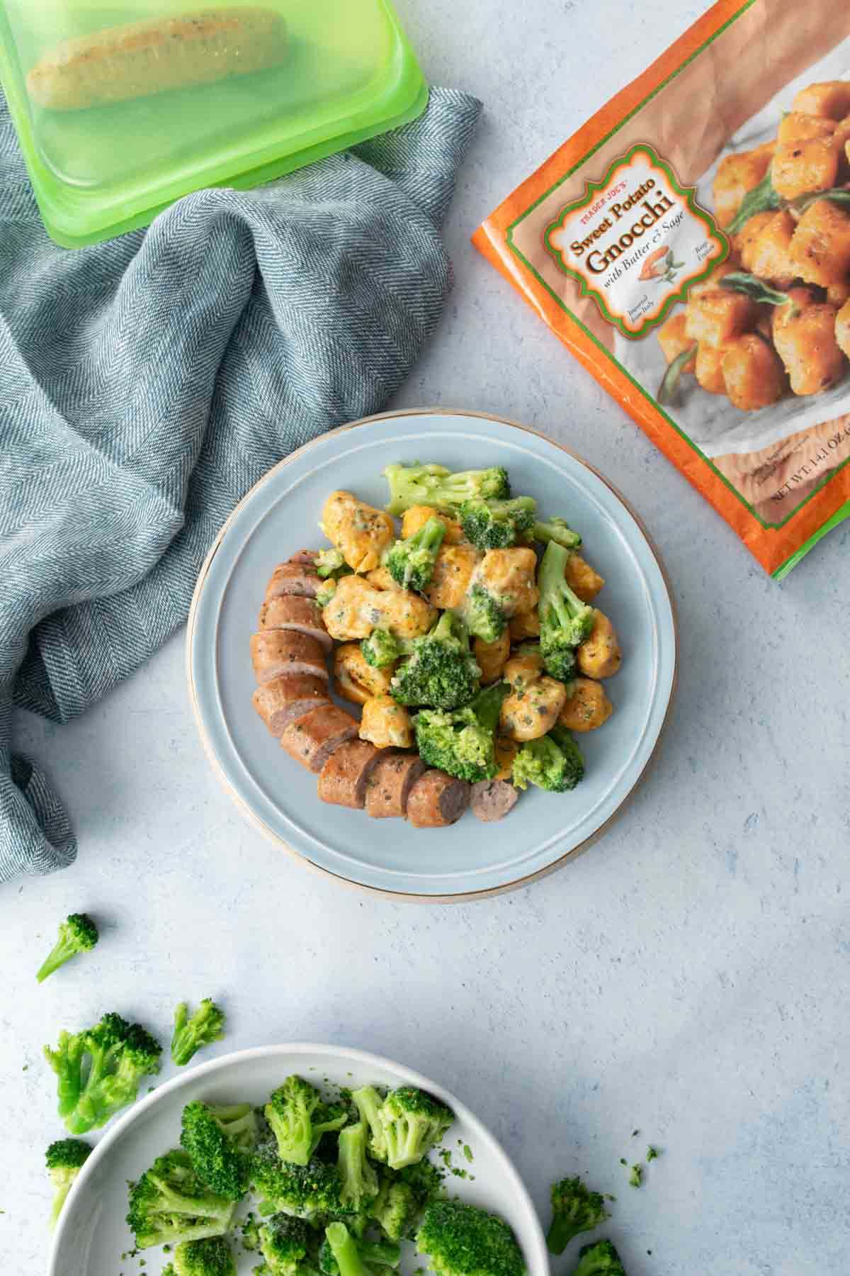 sweet potato gnocchi, broccoli and sliced sausage on blue plate