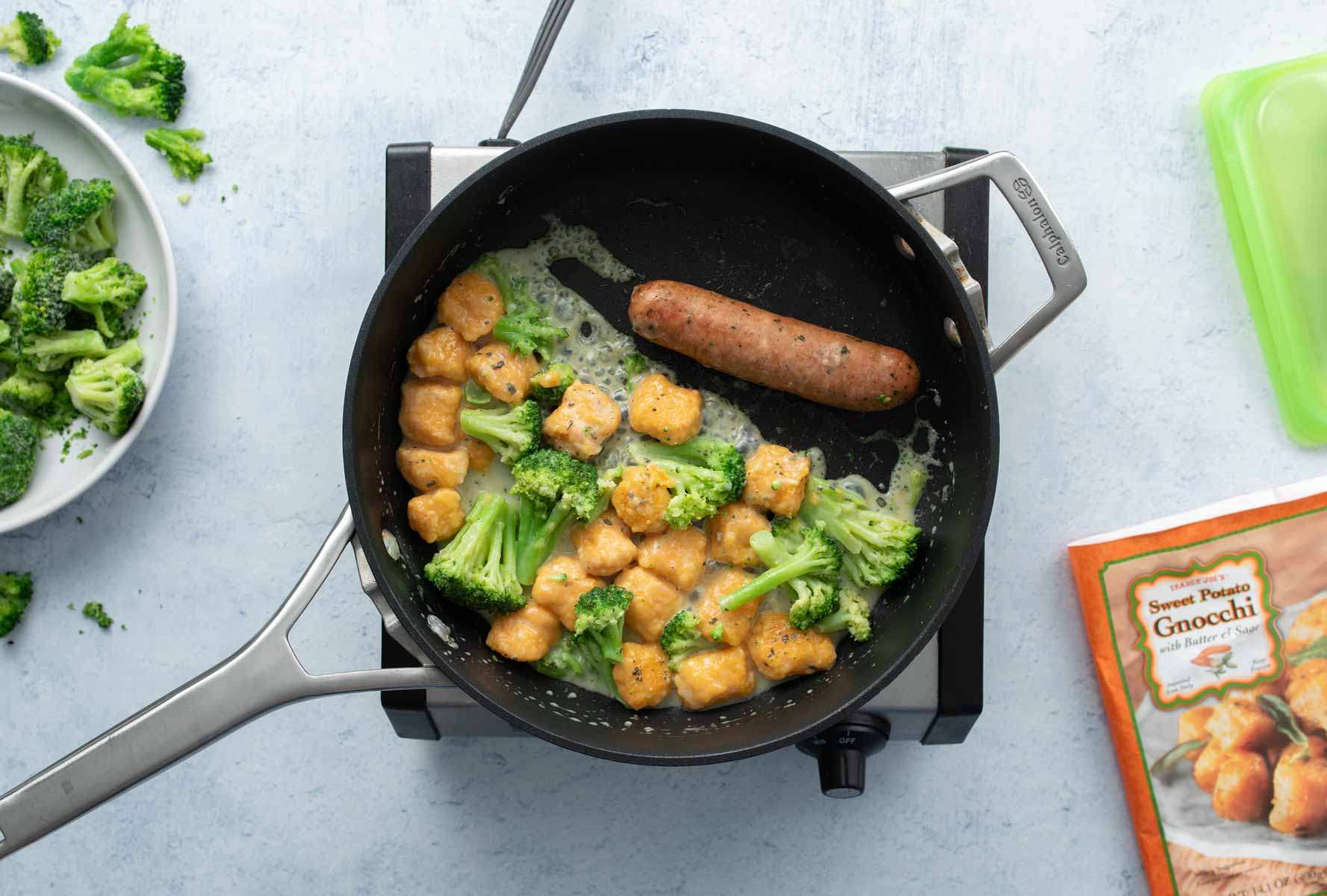 simmering sweet potato gnocchi, broccoli, sausage in skillet