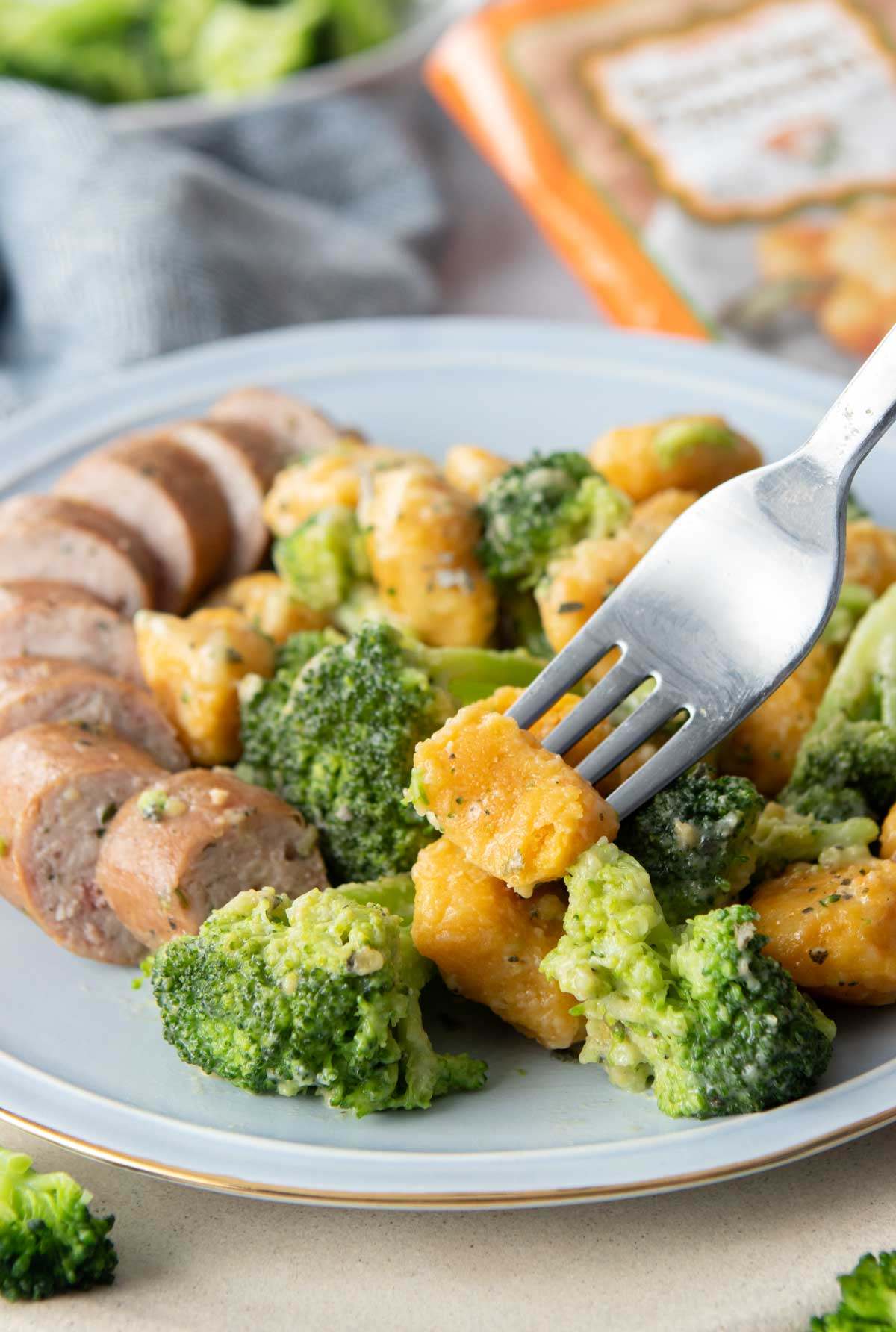 forkful of sweet potato gnocchi, with plate of food behind