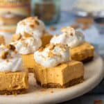 bite out of a pumpkin cheesecake bars on plate with more bars