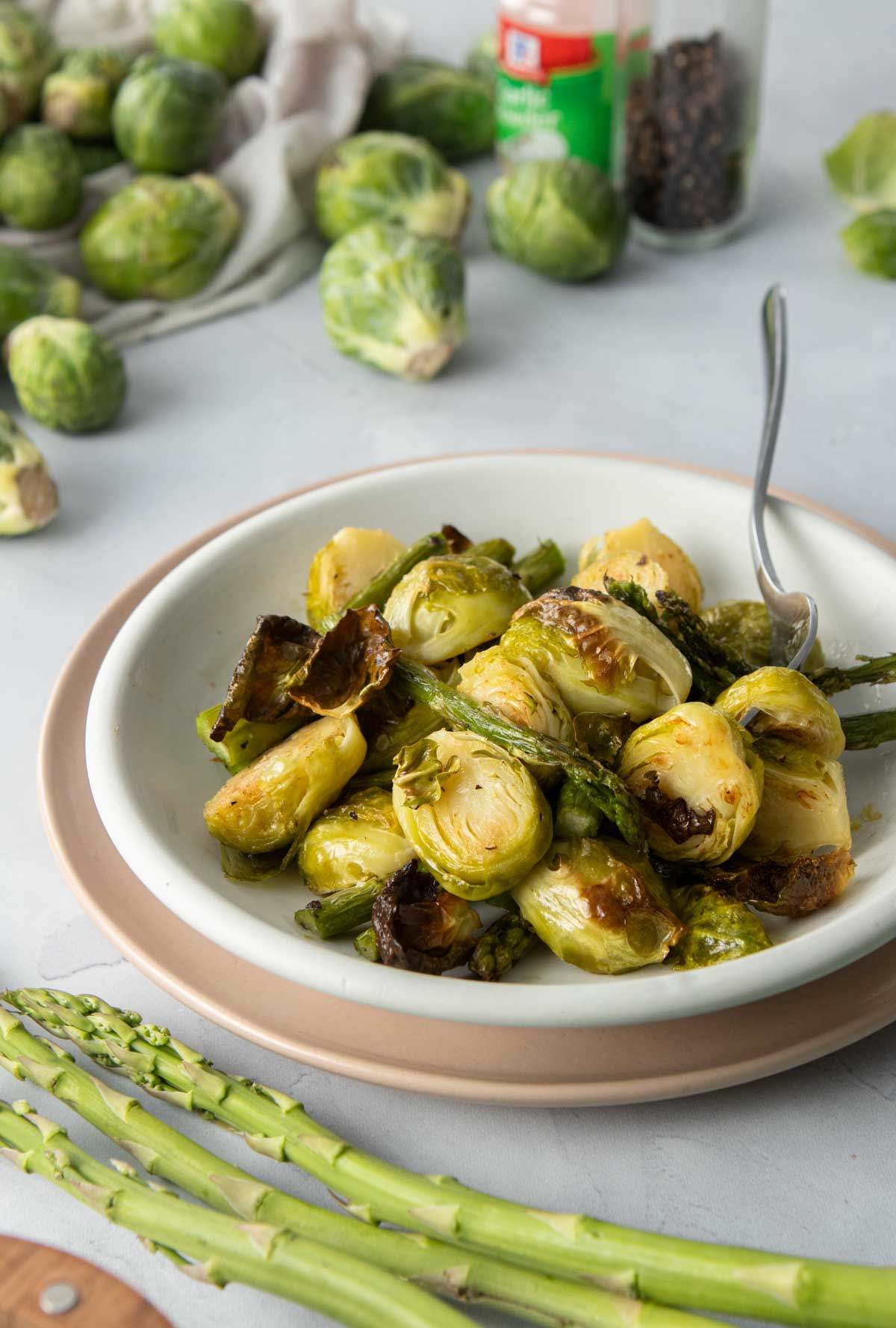 bowl of roasted asparagus and brussels sprouts with fork in it